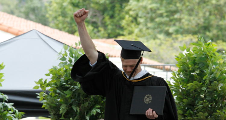 A graduate raises his fist in celebration