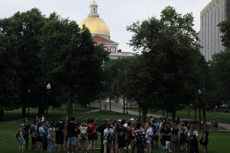 The students, all standing in a group, admire an ornate gold-domed building