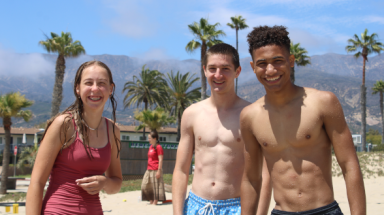 Three students pose for a photo at the beach