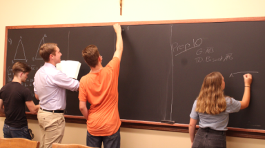 Students practice their propositions on the blackboard