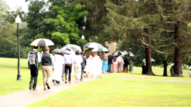 Students walk across campus under umbrellas