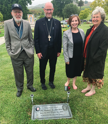 Bishop Conley visiting the grave of Rev. Ramon Decan with Fr. Decan's family
