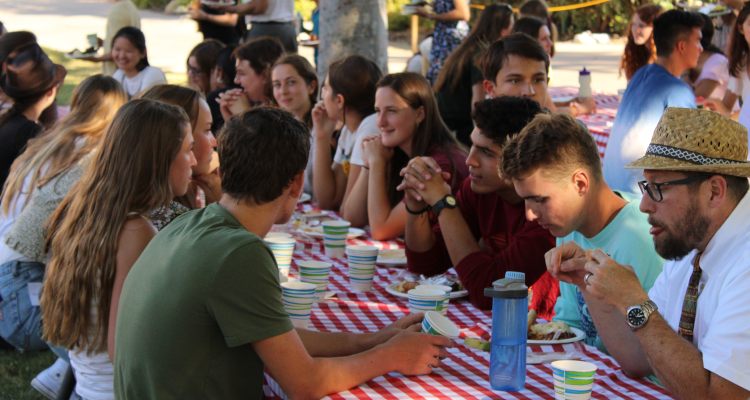 Summer programmers dine at brightly-colored outdoor picnic tables