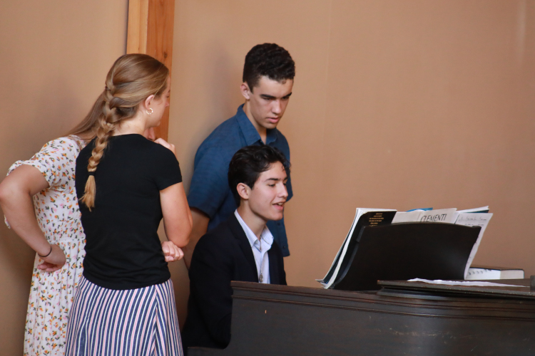 Students watch friend play the piano