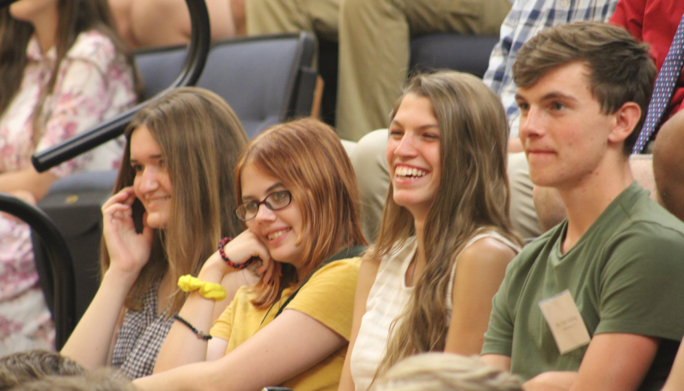 Closeup of four students in a row in the auditorium