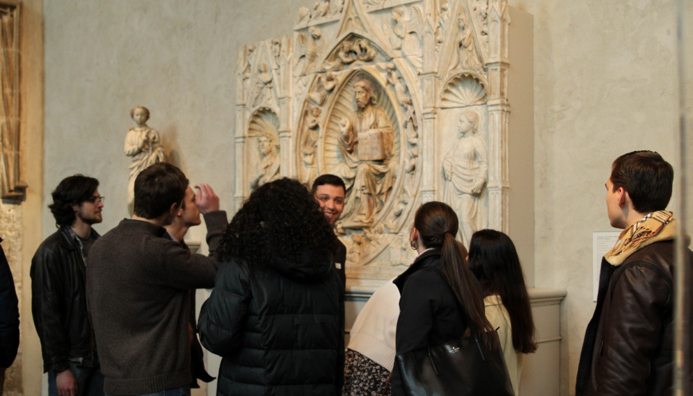 Students in front of a carven marble altar and reredos