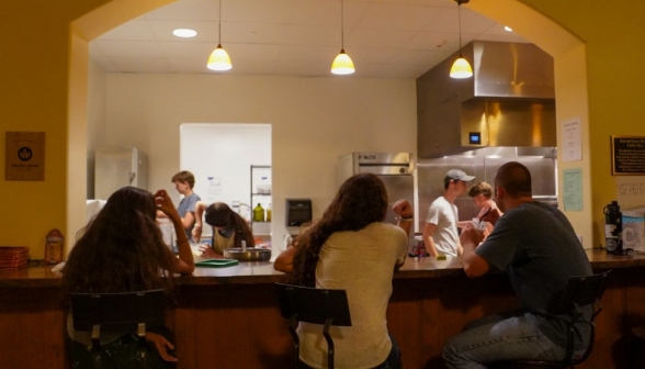 Students at the counter in the coffee shop. In the background, the baristas prepare orders.