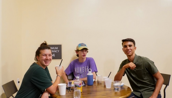 Three students pose at a table with their coffee