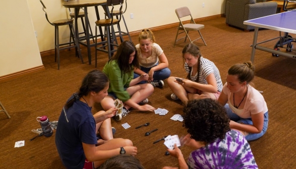 Cross-legged on the floor, students play a game of spoons