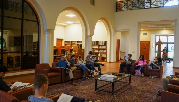 Students study in the armchairs in the main hall of the library