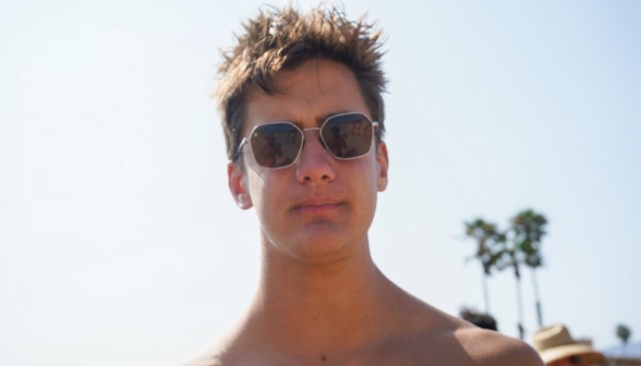 Closeup of a student with ocean-tousled hair, shades, and a serious expression on his face