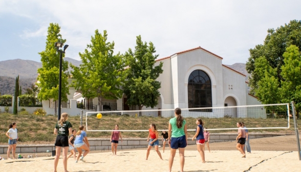 An all-women volleyball game plays out on the sand court