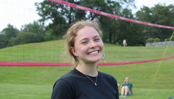 A smiling student afront the volleyball net