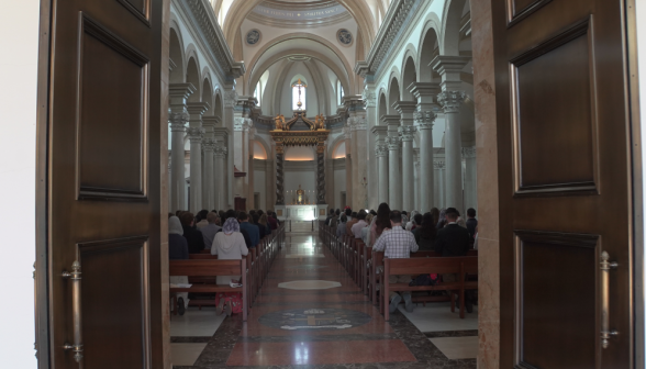 A view down the aisle from the doors, with people still in prayer in the pews