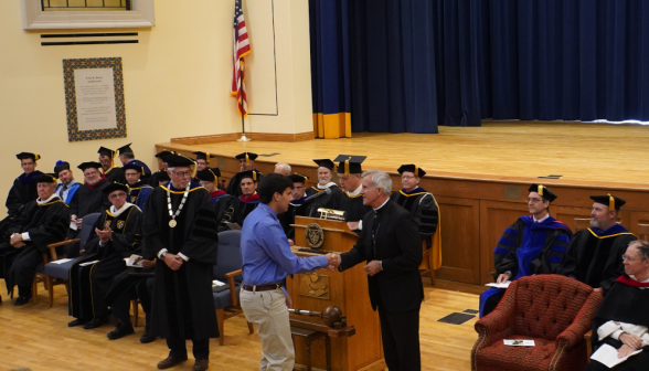 A student shakes the hand of the bishop as he is called up