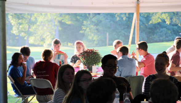 Students, parents, and visitors eat around the crowded tables as the sun begins to sink in the sky