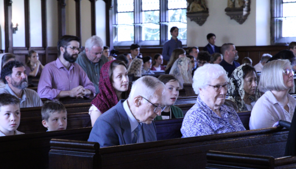 Before Mass, people sit or kneel in prayer in the pews