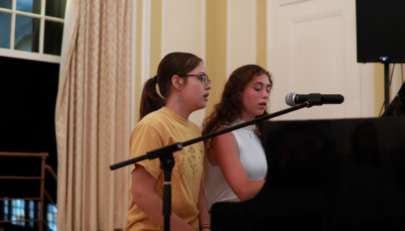 Two perform a duet on the piano while singing