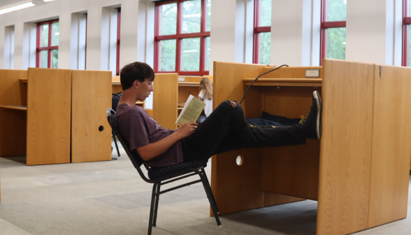 Leaning back in his chair, a student studies at an individual desk