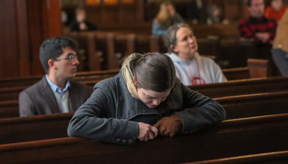 A student prays in one of the pews