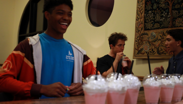 A student behind a row of pink drinks