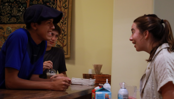 A prefect chats with students over the coffee shop counter