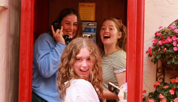 Three pose in a red telephone booth