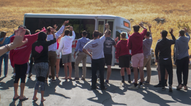 Students wave goodbye to a departing bus