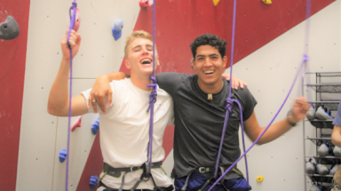 Two students pose for a photo at the rock-climbing wall