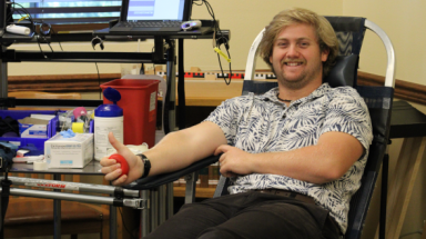 A student, about to have blood drawn, gives the thumbs-up