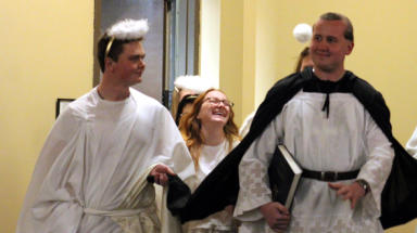 A student dressed as St. Thomas surrounded by students dressed as angels