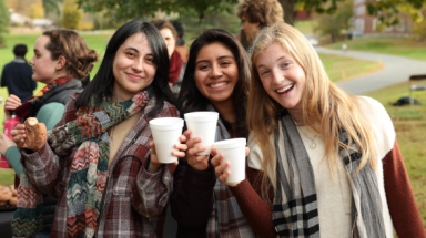 New England students celebrating the arrival of fall with scarves and cider