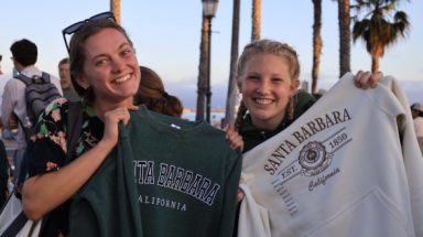 Two students hold up Santa Barbara sweatshirts