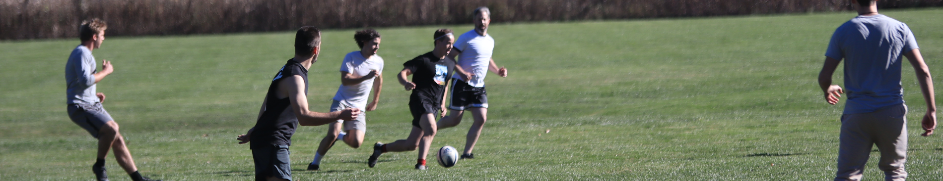 A student guides the ball down the field with others in pursuit